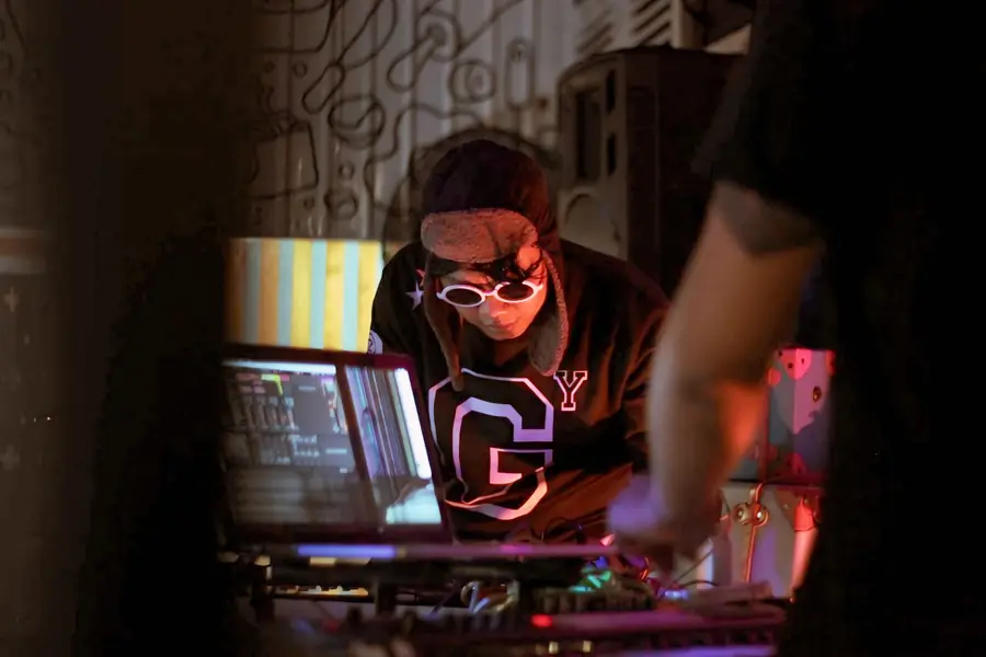 Welige in sunglasses behind a laptop and controllers