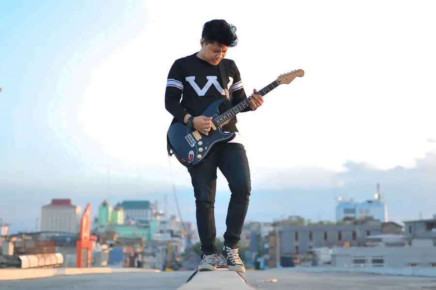 Welige with a guitar on a Pekanbaru rooftop