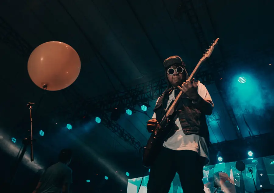 Welige on guitar under teal stage lights